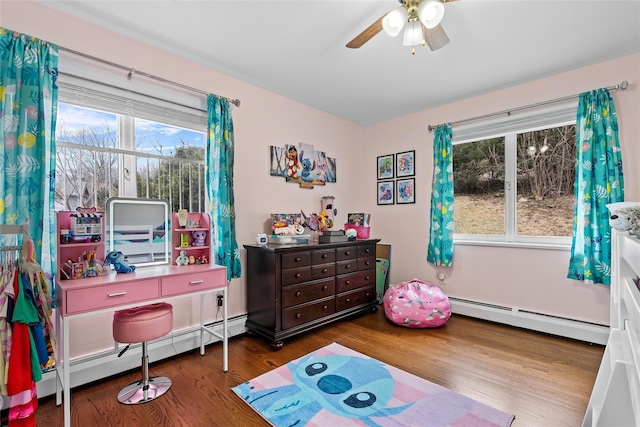bedroom featuring a baseboard heating unit, ceiling fan, and wood finished floors