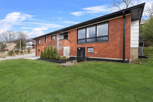 rear view of property with brick siding and a yard