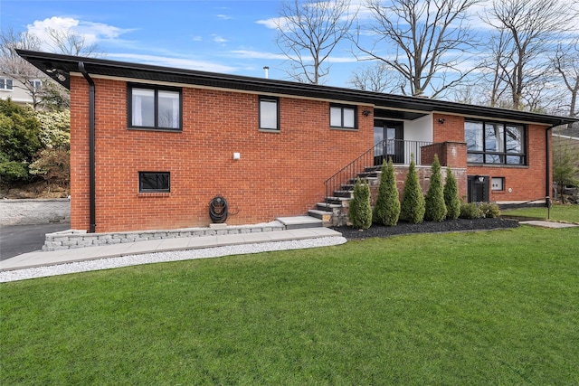 rear view of property with brick siding and a yard