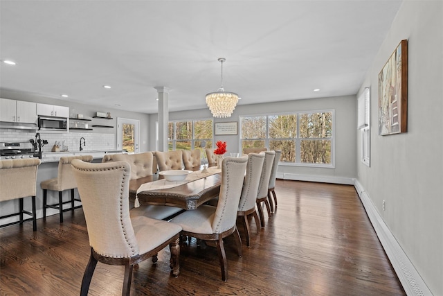 dining area with ornate columns, a notable chandelier, dark wood finished floors, and recessed lighting