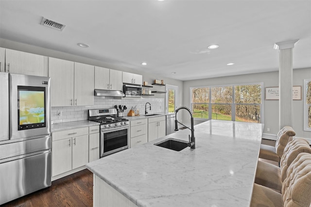 kitchen featuring under cabinet range hood, a sink, visible vents, and stainless steel appliances