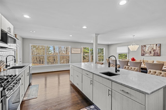 kitchen with stainless steel appliances, light stone countertops, a sink, and dark wood finished floors