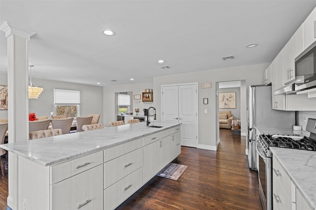 kitchen featuring visible vents, a sink, stainless steel appliances, dark wood-style floors, and a spacious island