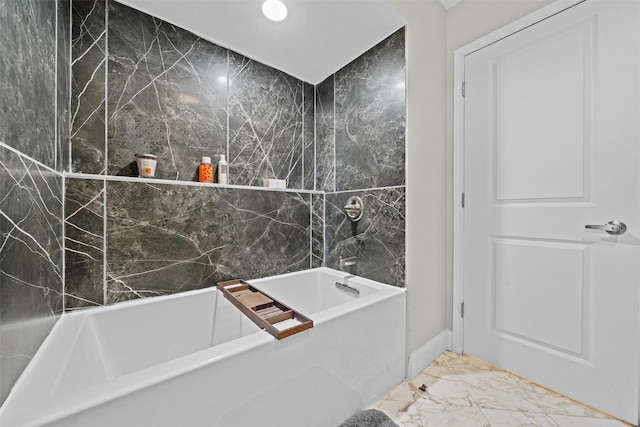 full bath with baseboards, marble finish floor, and a bathtub