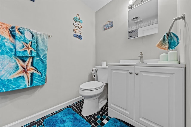 half bathroom featuring toilet, vanity, baseboards, and tile patterned flooring