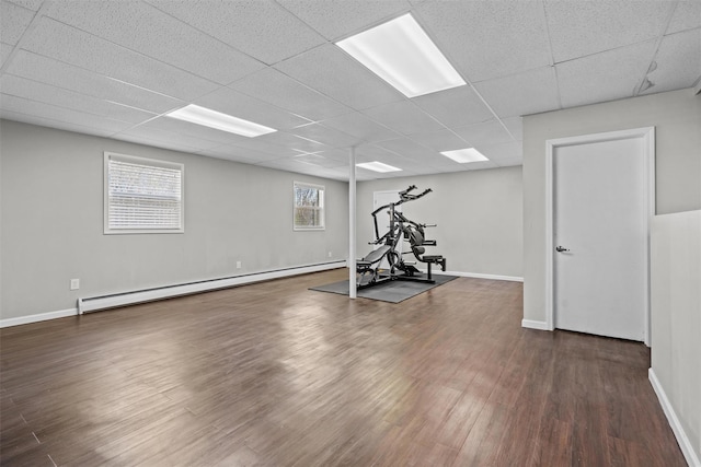 workout room featuring a baseboard radiator, a paneled ceiling, baseboards, and dark wood-style floors