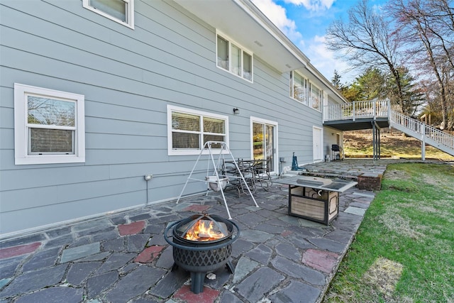 view of patio featuring a deck, a fire pit, and stairs