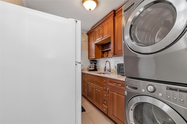 washroom featuring light tile patterned floors, a sink, stacked washing maching and dryer, laundry area, and a toaster