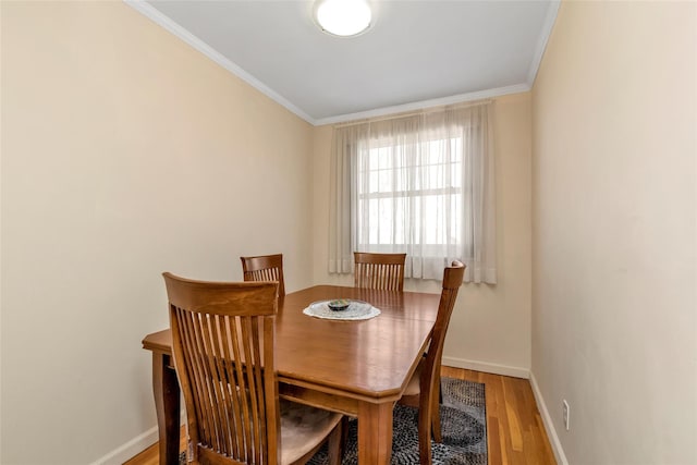 dining area featuring ornamental molding, baseboards, and light wood finished floors