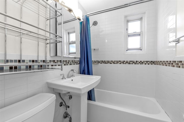 full bath with toilet, tile walls, a wealth of natural light, and shower / bath combo with shower curtain