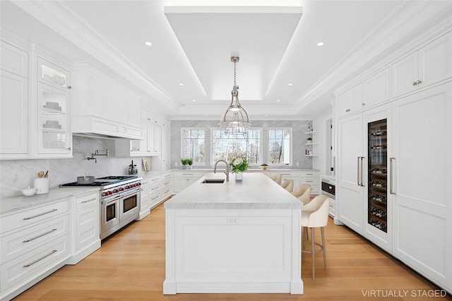 25 Fresh Pond Rd, North Haven, NY 11963 - kitchen featuring light countertops, a tray ceiling, a sink, white cabinets, and range with two ovens