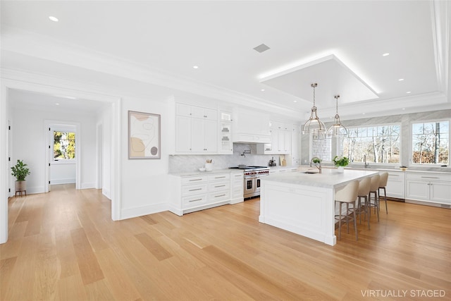 25 Fresh Pond Rd, North Haven, NY 11963 - kitchen featuring white cabinetry, light countertops, a breakfast bar, a raised ceiling, and range with two ovens