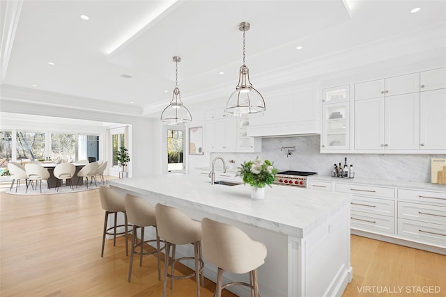 25 Fresh Pond Rd, North Haven, NY 11963 - kitchen featuring a tray ceiling, light wood finished floors, white cabinets, and a sink