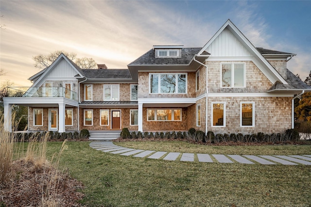 25 Fresh Pond Rd, North Haven, NY 11963 - back of property at dusk featuring board and batten siding, a balcony, a porch, and a yard