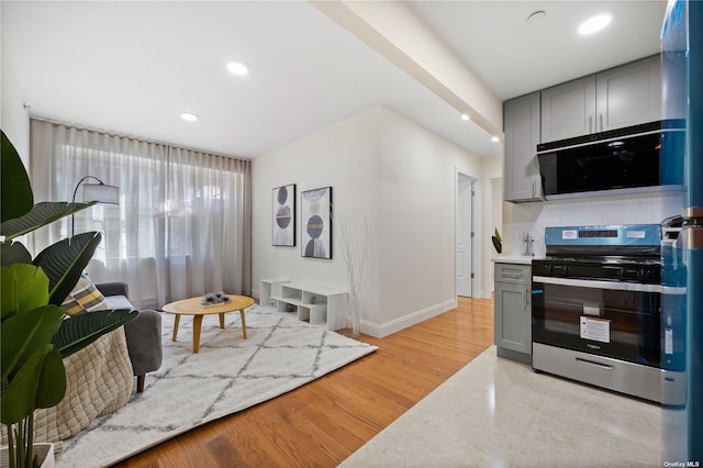 kitchen featuring light wood-type flooring, recessed lighting, gray cabinets, baseboards, and gas stove