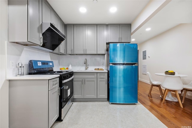 kitchen with freestanding refrigerator, range with gas stovetop, a sink, and gray cabinetry