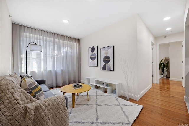 living area with baseboards, arched walkways, light wood-style floors, and recessed lighting