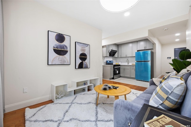 living room featuring baseboards, light wood-style flooring, and recessed lighting
