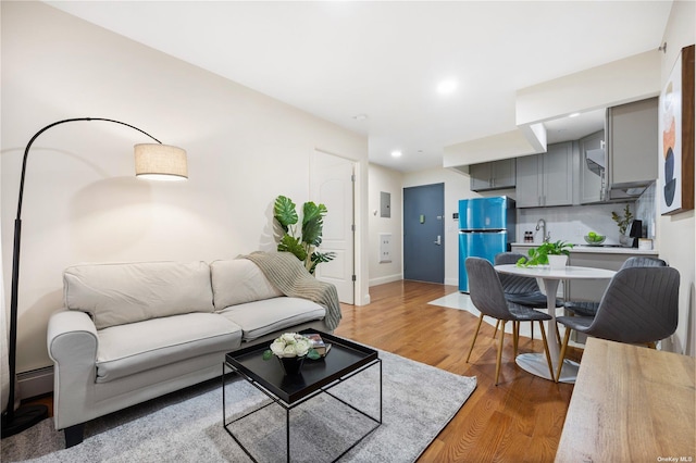 living room with baseboards, baseboard heating, light wood-style flooring, and recessed lighting