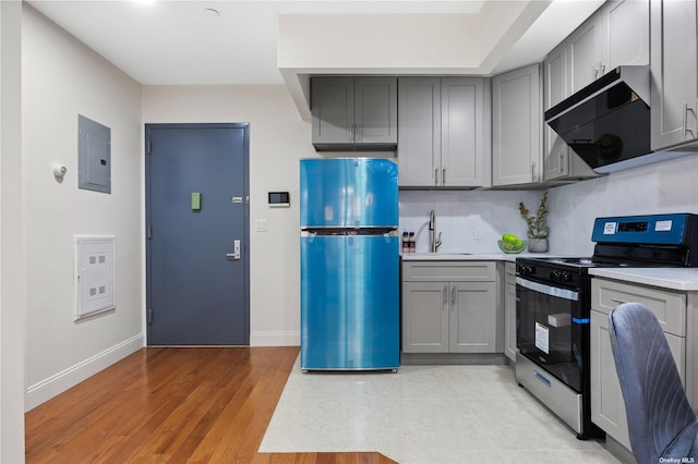 kitchen with light countertops, gray cabinets, electric range, freestanding refrigerator, and electric panel