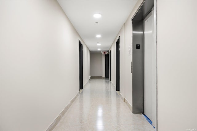 hallway with baseboards and elevator