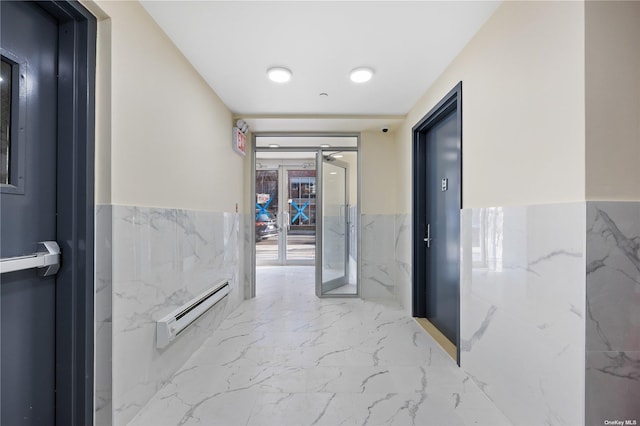 hall featuring marble finish floor, wainscoting, and a baseboard radiator