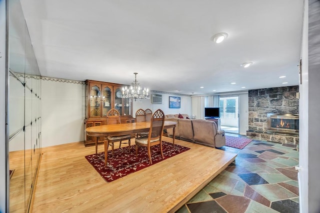dining area with a chandelier and a stone fireplace