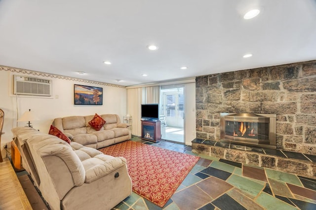 living area with a wall mounted AC, recessed lighting, and a stone fireplace