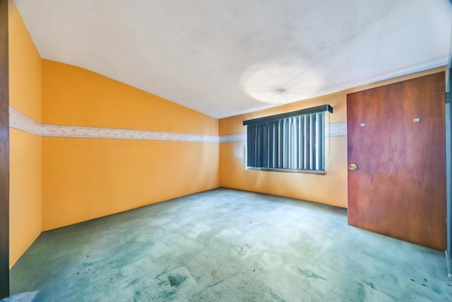 empty room with carpet floors and lofted ceiling