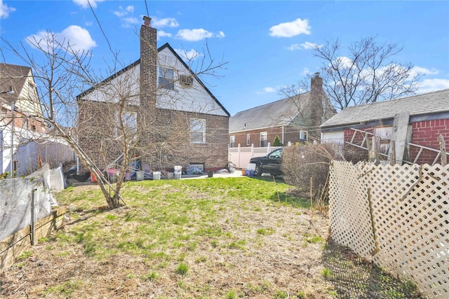 183-65 Elmira Ave, Saint Albans, NY 11412 - rear view of house with brick siding, a lawn, fence, and a chimney