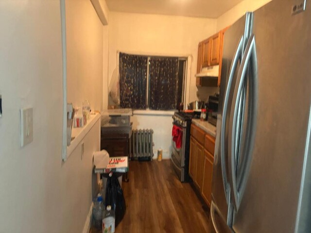 661 E 228th St, Bronx, NY 10466 - kitchen with radiator, under cabinet range hood, brown cabinetry, appliances with stainless steel finishes, and dark wood-style flooring