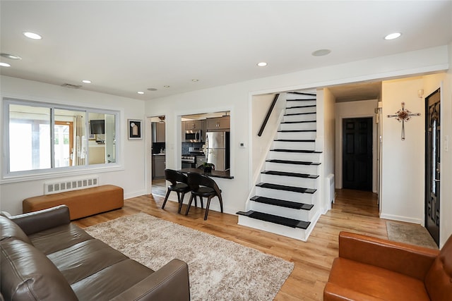 living room with stairway, light wood finished floors, and recessed lighting
