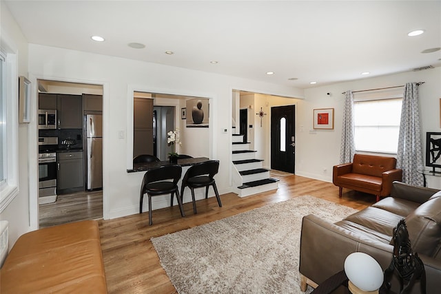 living area featuring baseboards, visible vents, light wood-style flooring, and recessed lighting