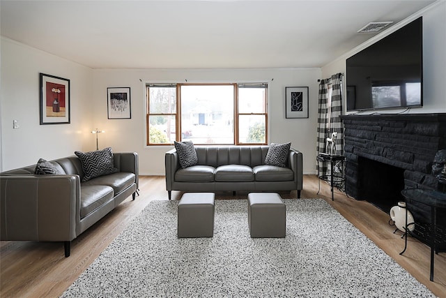 living room with visible vents, a fireplace, and wood finished floors