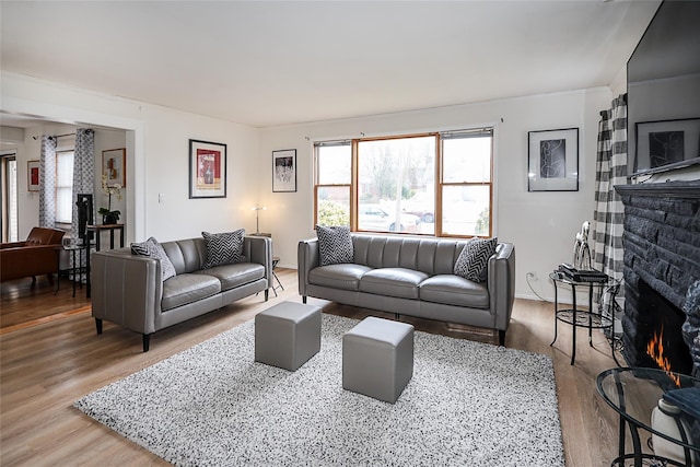 living area with a warm lit fireplace and wood finished floors