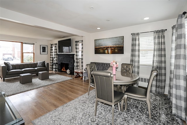 dining room with recessed lighting, a lit fireplace, and wood finished floors