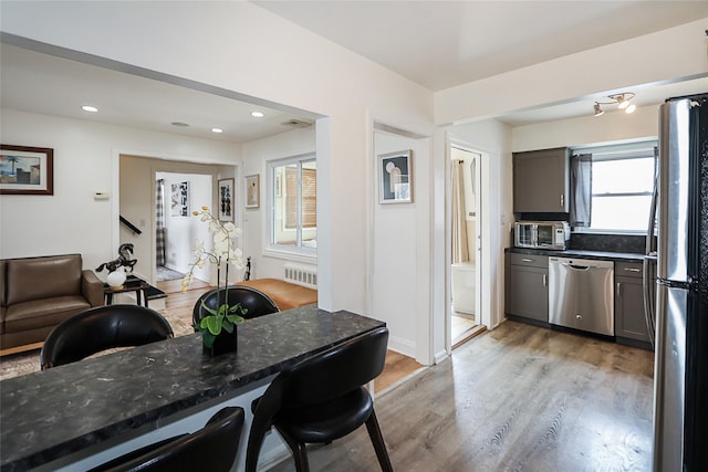 dining room with light wood-style flooring, radiator heating unit, and recessed lighting