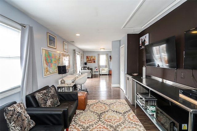 living room with dark wood-style flooring, baseboards, and attic access