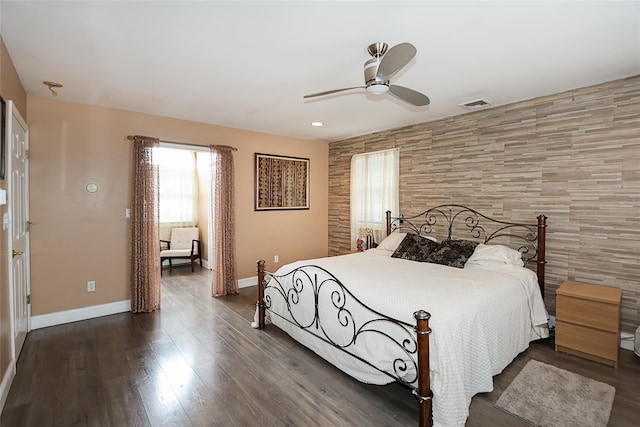 bedroom featuring an accent wall, a ceiling fan, wood finished floors, baseboards, and visible vents