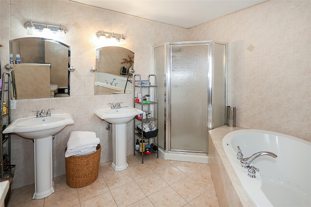 full bathroom featuring tile walls, a bath, a shower stall, tile patterned floors, and a sink