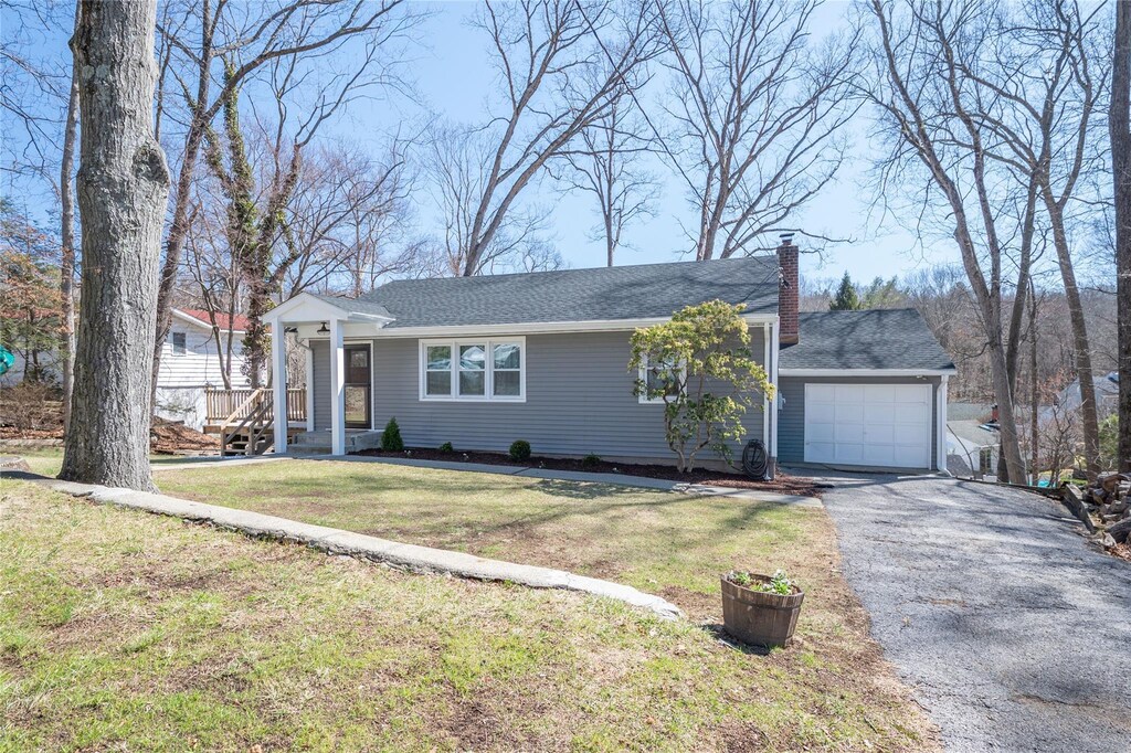 view of front of home featuring a chimney, a front yard, an attached garage, and aphalt driveway