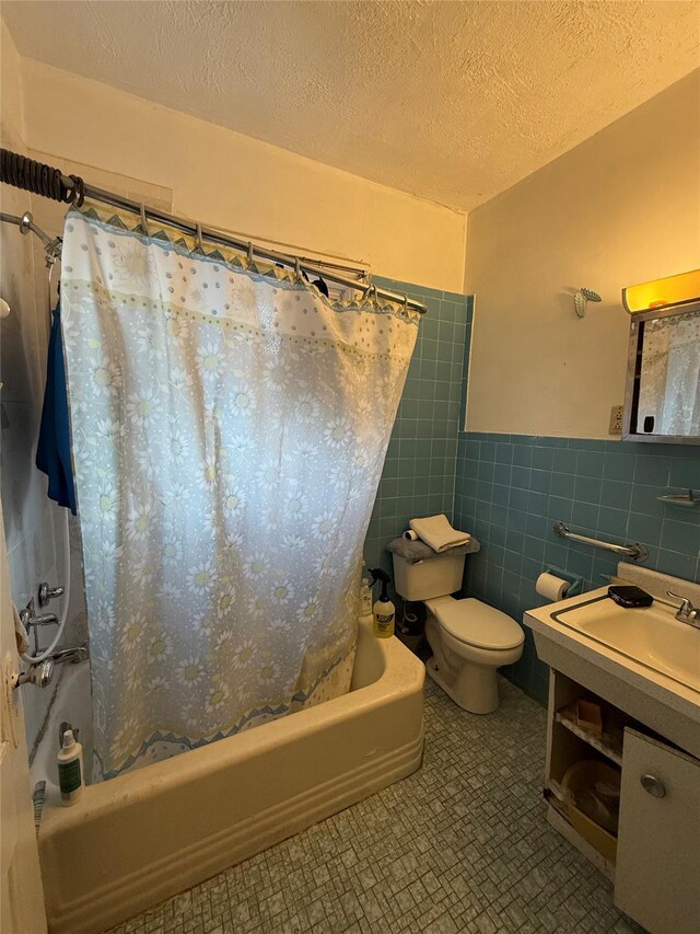 39 Rathbun Ave, White Plains, NY 10606 - full bathroom featuring tile walls, a textured ceiling, toilet, shower / bath combo with shower curtain, and wainscoting