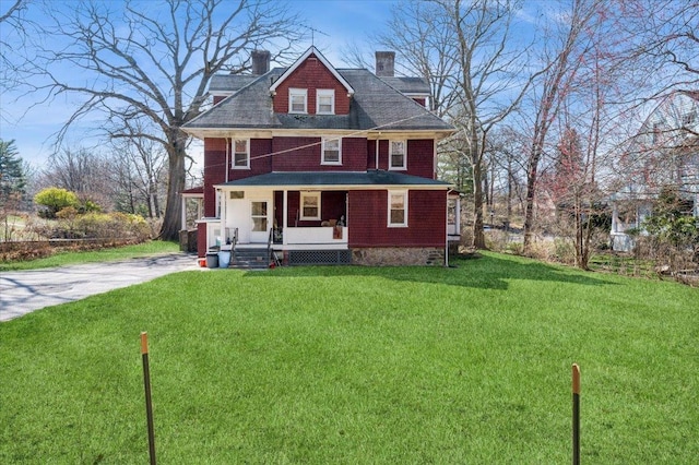 american foursquare style home featuring a front lawn, a chimney, and a porch