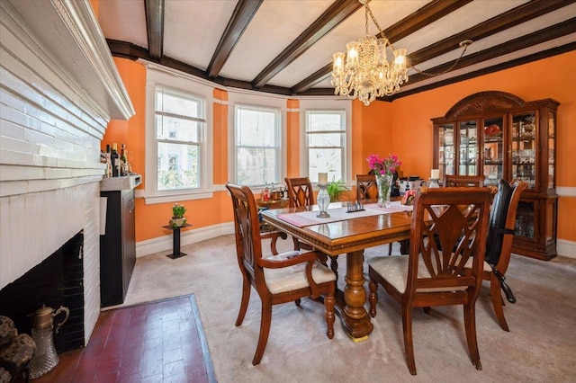 dining area featuring a wealth of natural light, a notable chandelier, beamed ceiling, and a fireplace