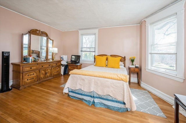 bedroom featuring baseboards, a textured ceiling, and wood finished floors