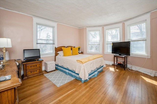 bedroom featuring a textured ceiling, multiple windows, and light wood-type flooring