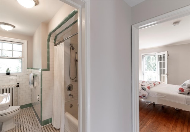 bathroom with radiator heating unit, wood-type flooring, toilet, and shower / bath combination with curtain