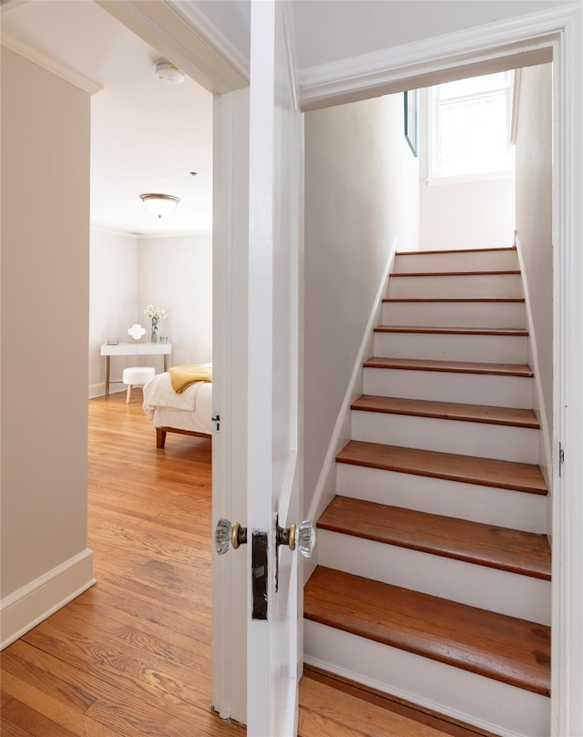 staircase with baseboards, ornamental molding, and wood finished floors