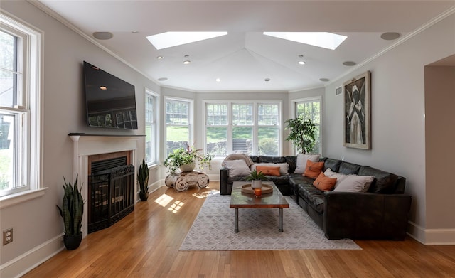 living room with a skylight, crown molding, and a fireplace with flush hearth
