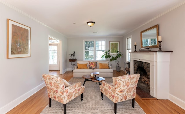 living room with a fireplace with raised hearth, baseboards, ornamental molding, and light wood-type flooring